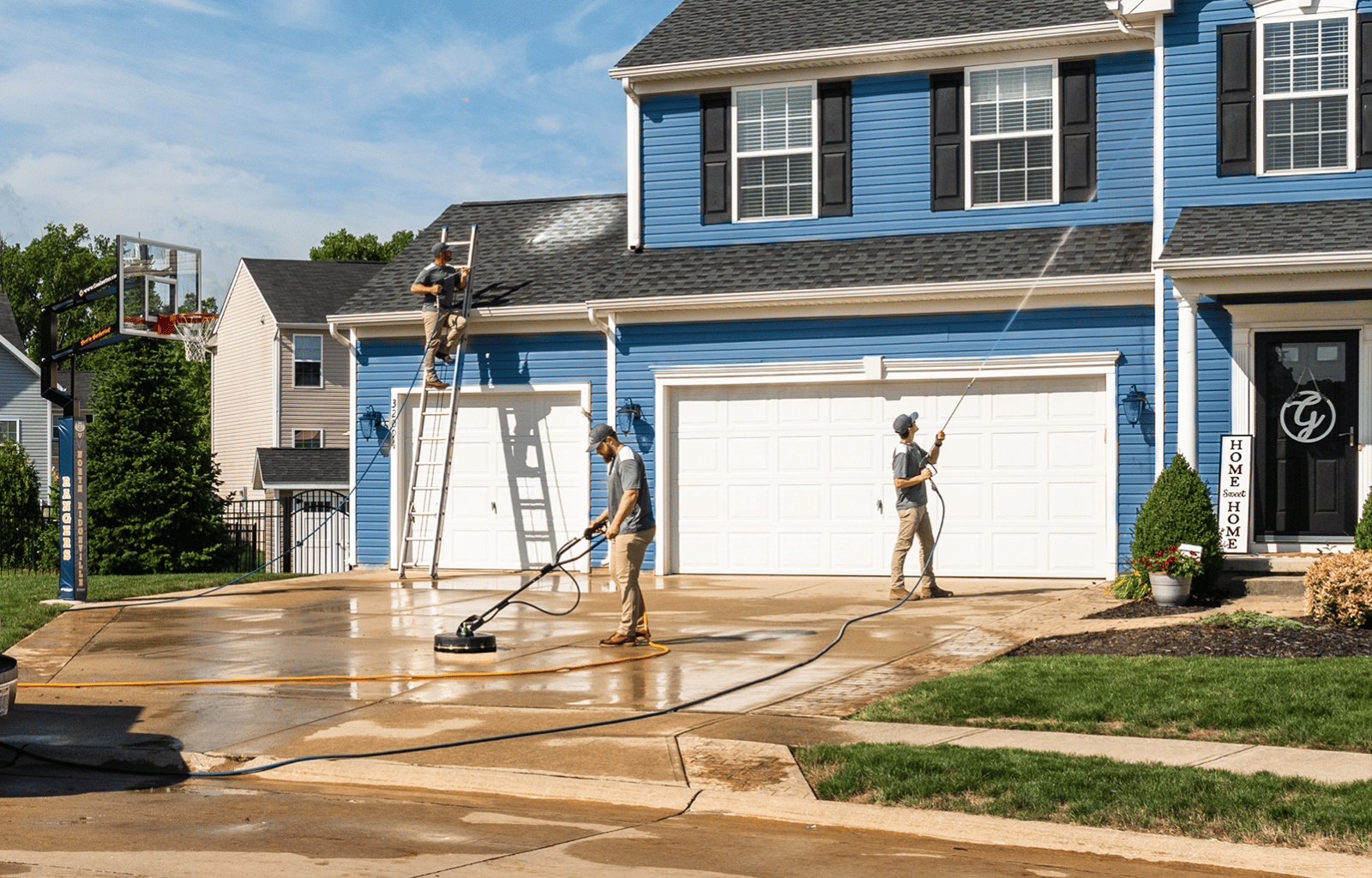 Pristine Clean power washers cleaning siding, roof, and driveway of home